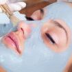 Girl with facial mask lying in beauty health spa center.